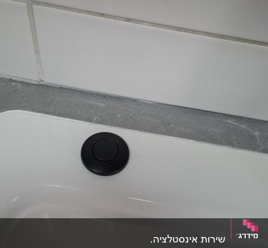 כיור עם כפתור שחור על משטח אפור